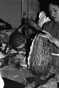Black and white photo of woman building a piñata.